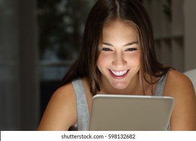 Close Up Of A Single Girl Watching Media Content On Line In A Tablet With The Light Of The Screen In Her Face In The Living Room At Home