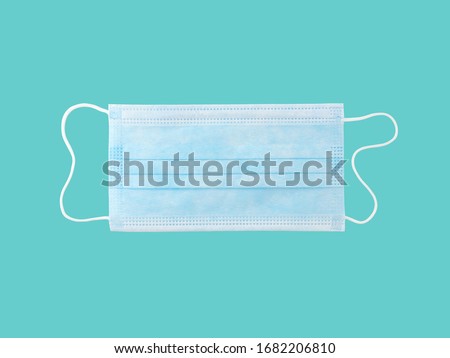 close up single light blue surgical mask (medical face mask) with white rope strap for prevent germs while performing surgery or protective coronavirus (COVID-19) outbreak isolated on cyan background
