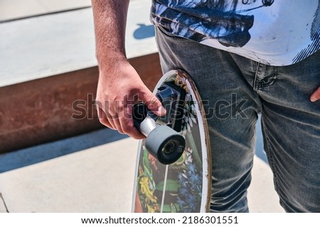 Close up of a skateboarder holding his skateboard after a hard day of training