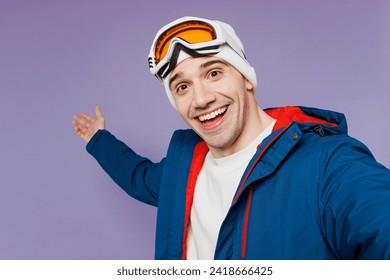 Close up skier man wear blue windbreaker jacket ski goggles mask hat do selfie shot mobile cell phone point aside spend extreme weekend winter season in mountains isolated on plain purple background - Powered by Shutterstock