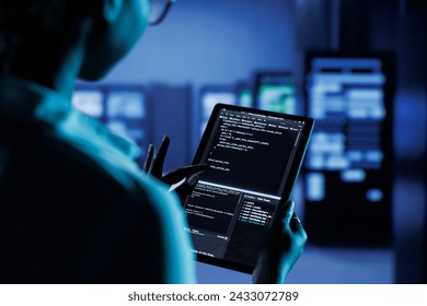 Close up of skilled worker running code and programming on laptop, troubleshooting and upgrading high tech facility designed to accommodate multiple clusters of fully operational server units - Powered by Shutterstock