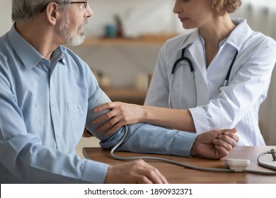 Close Up Skilled Young Female Family Doctor Gp Physician Measuring Blood Pleasure Of Mature Middle Aged Male Patient At Checkup Meeting, Cardiovascular Disease Prevention, Medical Healthcare Concept.