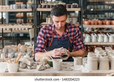 Close up skillful caucasian man makes a handle to the clay cup on the background of pottery workshop. Artwork and creative concept. - Powered by Shutterstock