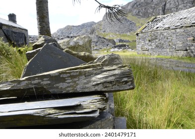 A close up of a Slate Dry Stone Wall covered in Lichens in an abandoned Quarry in Snowdonia National Park with Ruins of Miners Houses and Animal Barn. It's a rugged landscape in the Welsh Mountains.