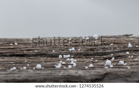Close up of sleet fall on rough cut rail of corral fence