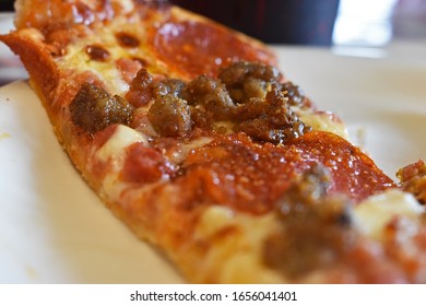 Close Up Of A Slice Of All Meat Pizza On A White Plate