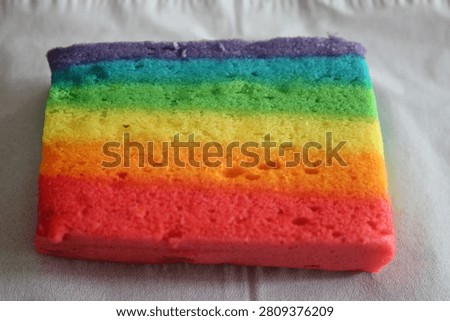 Close up of a slice of rainbow layered cake showing vibrant colors from red to purple This colorful confection is perfect for celebrations