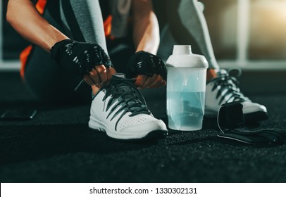 Close Up Of Slim Caucasian Woman Tying Shoelace In Gym At Night. Try And Fail, But Don't Fail To Try.