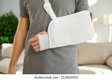 Close up of sling on broken arm of man he needs to wear during rehabilitation period. Unknown male patient wearing immobilizer after car accident or after sports injury. Orthopedics concept.