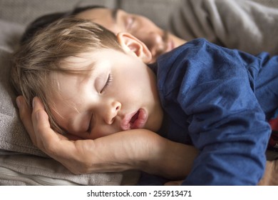 Close Up Of A Small Boy Fallen Asleep On The Couch With His Father