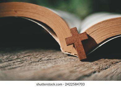 close up small cross and book on wood table, copy space for text
