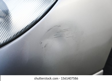 Close Up Of Small Dent And Scratches On Silver Gray Car. Car With Damage From Crash Accident, Parking Lot Or Traffic.