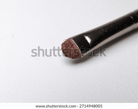 Close Up of Small Makeup Brush Tip with Soft Bristles on White Textured Background