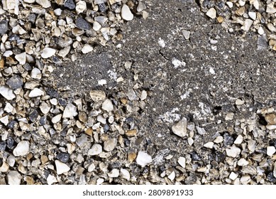 Close up of small multi colored pebbles embedded in weathered concrete texture