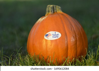 Close Up Small Orange Gourd Ripe Mini Pumpkin In Green Backyard Grass In Yellow Golden Afternoon Light, I Voted Early November US American Election Voting Sticker Patriotic Red White Blue Waving Flag