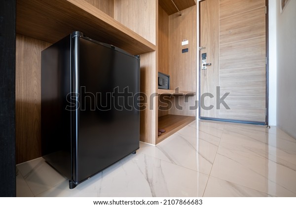 Close small\
refrigerator under the wood counter and in front of enter door\
delux room at resort and\
hotel.