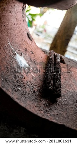 Close up of a small spider web and rusted threaded bolts inside a weathered metal pipe