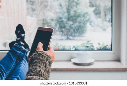 close up smartphone in hand of women with window background in snow day,relaxing in room