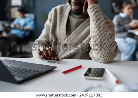 Close up of smiling African American man playing with fingerboard on table at office workplace