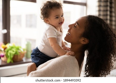 Close Up Smiling African American Woman Hugging Adorable Little Daughter, Standing At Home, Beautiful Young Mum Holding Cute Toddler Girl, Enjoying Tender Moment Together, Childcare Concept