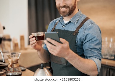 Close Up Of Smiling Barista Drinking Coffee And Scrolling Through Social Media Feed During Lunch 