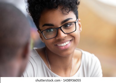 Close up of smiling black biracial girl in glasses talk feel happy have pleasant conversation with friend, overjoyed positive beautiful african American millennial in spectacles chatting or speaking
