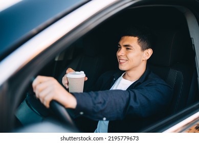 Close up of a smiling businessman driving a car while drinking coffee. He is looking at camera - Powered by Shutterstock