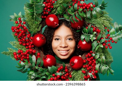 Close up smiling cheerful merry little kid teen girl posing hold looking camera through Christmas handmade wreath isolated on plain green background studio. Happy New Year celebration holiday concept - Shutterstock ID 2396398865