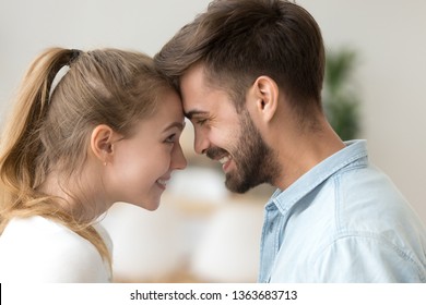 Close up smiling couple in love touching forehead, happy affectionate wife and husband enjoying tender moment at home, newlyweds caressing each other, romantic date, first kiss concept