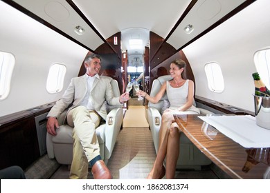 Close up of a smiling couple making a toast with champagne glasses in a private jet
