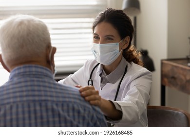 Close up smiling female doctor wearing protective face mask touching senior patient shoulder, physician comforting and supporting mature man at medical appointment, psychological help concept - Powered by Shutterstock