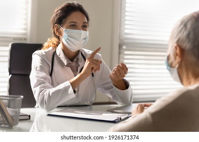 Close Up Smiling Female Doctor Wearing Medical Face Mask Consulting Mature Patient At Meeting In Hospital, Happy Therapist Physician And Senior Woman Discussing Checkup Or Treatment Results