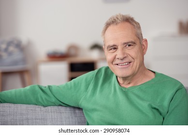Close up Smiling Middle Aged Man in Casual Green Shirt, Sitting at the Sofa While Looking Into Distance and Thinking of Something