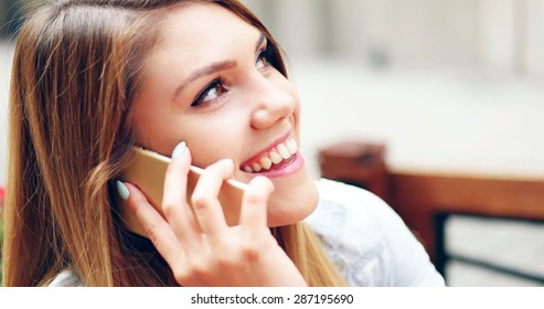 Close up Smiling Pretty Young Woman Talking to SOmeone on Mobile Phone While Drinking at the Cafe - Shutterstock ID 287195690