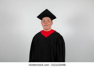 Close Up Smiling Red Cheeked Graduate Male Student In Mortar Board And Bachelor Gown Isolated On White Background