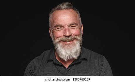 Close Up Of Smiling Senior Man With A White Beard. Portrait Of A Senior Man Isolated On Black Background.