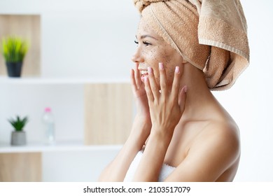 Close up of smiling woman applying coffee scrub on face - Shutterstock ID 2103517079
