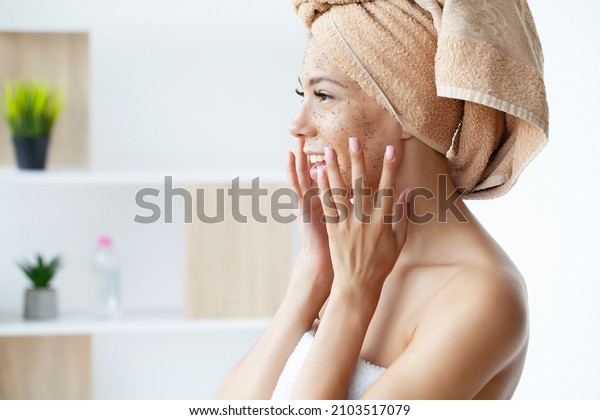 Close\
up of smiling woman applying coffee scrub on\
face