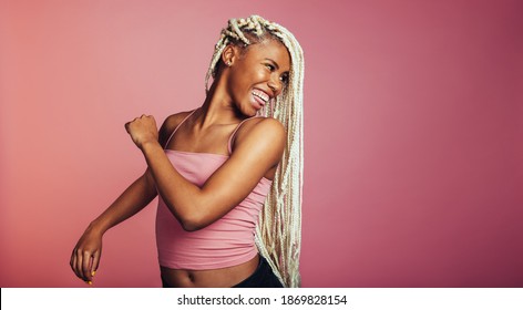 Close Up Of Smiling Woman Looking Back Over Her Shoulder. African American Woman With Braided Hair On Pink Background.