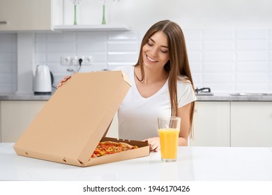 Close Up Of Smiling Woman Opening Box With Pizza In Kitchen. Concept Of Eating Delicious Pizza And Drinking Juice.