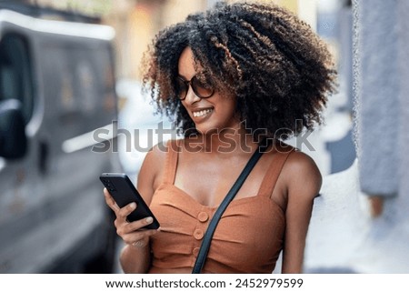 Similar – Frau mit Afro-Haaren auf der Straße, die ein Smartphone hält.