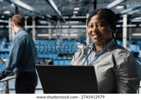 Close up of smiling worker in server farm next to colleague upgrading hardware for increased storage capacity. Jolly african american data center admin and coworker doing maintenance