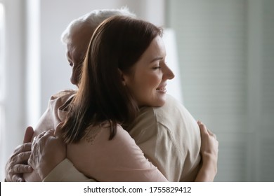 Close up smiling young beautiful woman hugging older man, happy grownup daughter and mature father enjoying tender moment with closed eyes, cuddling, two generations, good family relationship
