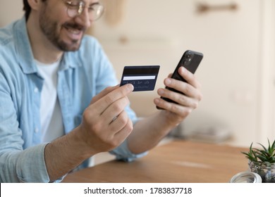 Nahaufnahme eines lächelnden jungen kaukasischen Mannes halten Handy machen Online-Bezahlung mit Kreditkarte, glückliche männliche Einkäufe online über Smartphone, Internet-Banking-System auf Gadget verwenden