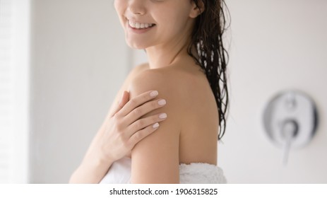 Close Up Of Smiling Young Caucasian Woman In Towel Touch Soft Healthy Body Skin After Natural Organic Lotion Or Cream. Happy Female Do Daily Beauty Procedures, Wash Clean In Bath. Skincare Concept.