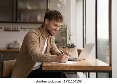 Close up smiling young man using laptop, writing, taking notes, watching webinar, training, involved in internet lesson, motivated positive student studying online at home, looking at laptop screen - Powered by Shutterstock