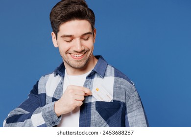 Close up smiling young man wears shirt white t-shirt casual clothes hold in hand put mock up of credit bank card into pocket isolated on plain blue cyan background studio portrait. Lifestyle concept - Powered by Shutterstock