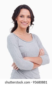 Close Up Of Smiling Young Woman With Her Arms Folded Against A White Background