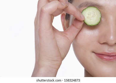 Close Up Of Smiling Young Woman Holding Up A Cucumber Slice Over Her Eyes