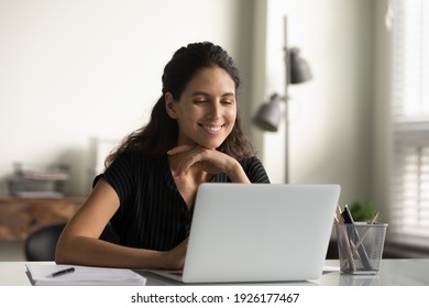 Close up smiling young woman looking at laptop screen, reading good news in message, watching video, chatting in social network or shopping online at home, enjoying leisure time with computer